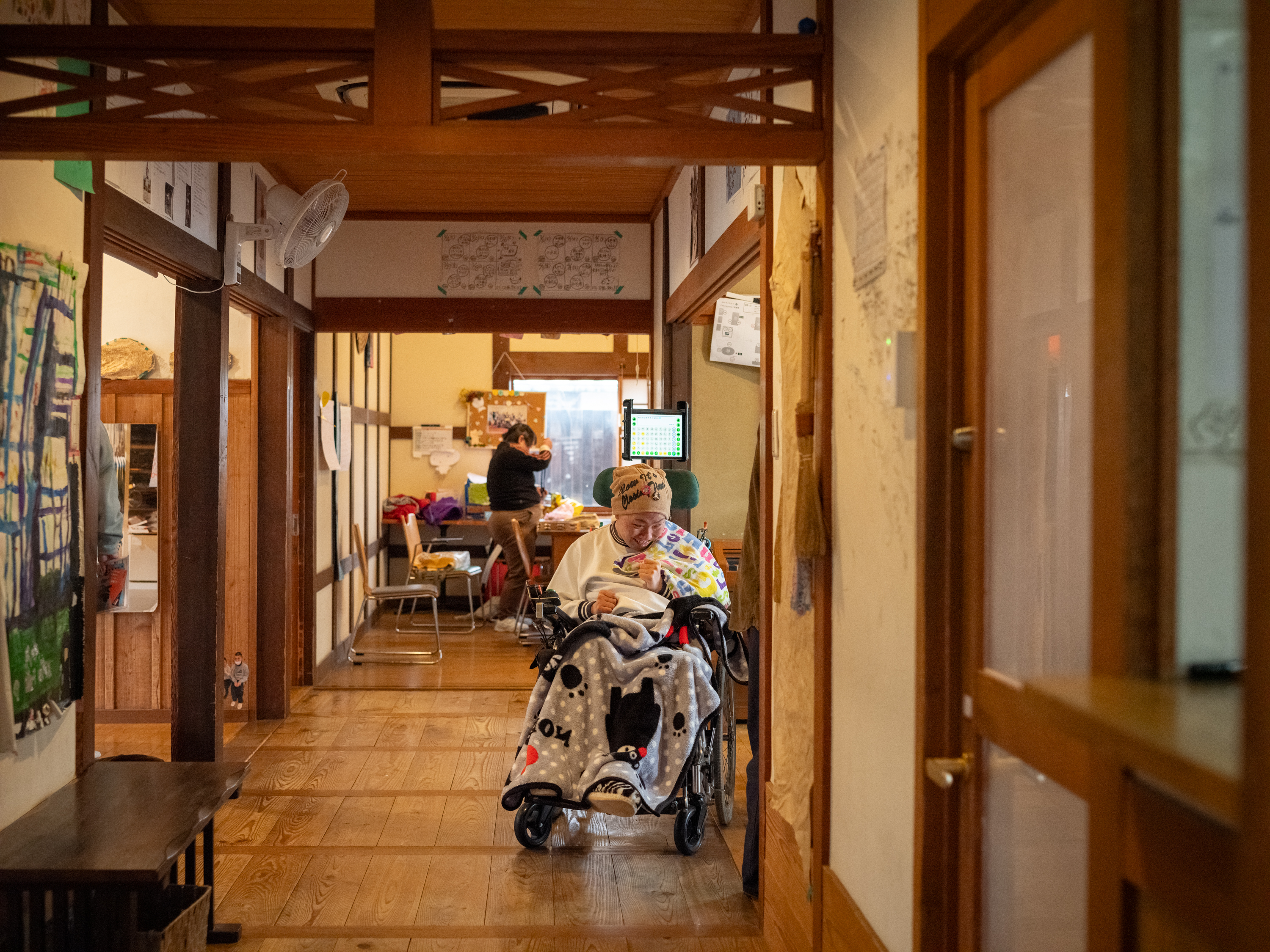 【写真】廊下を移動するおおはらさん、車椅子を活用している