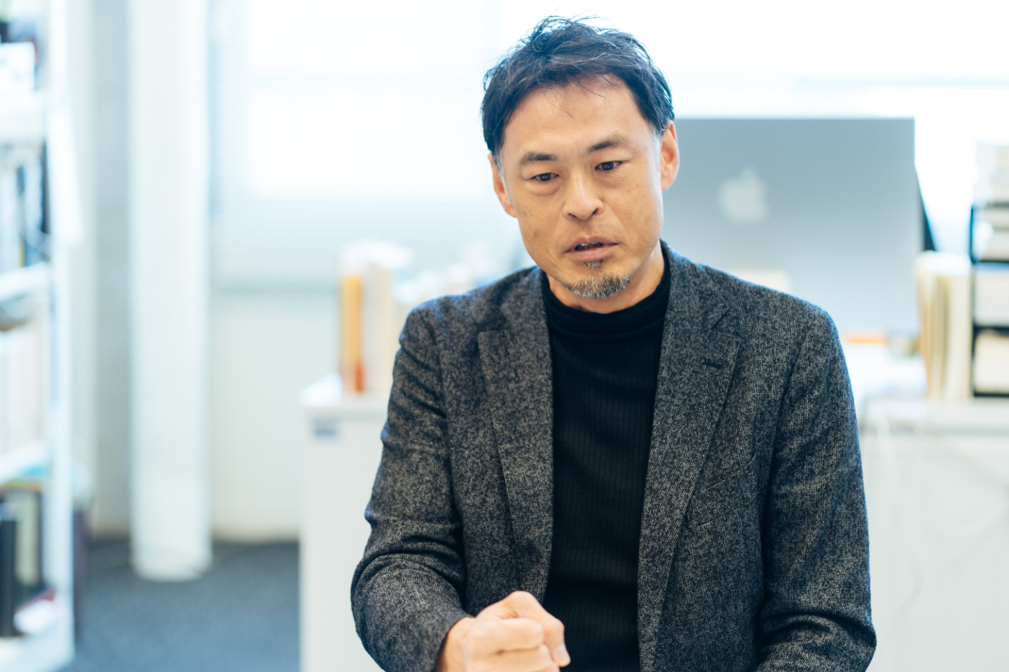 【写真】ジャケットを着て座る平尾さんが、拳を握りながら話す姿