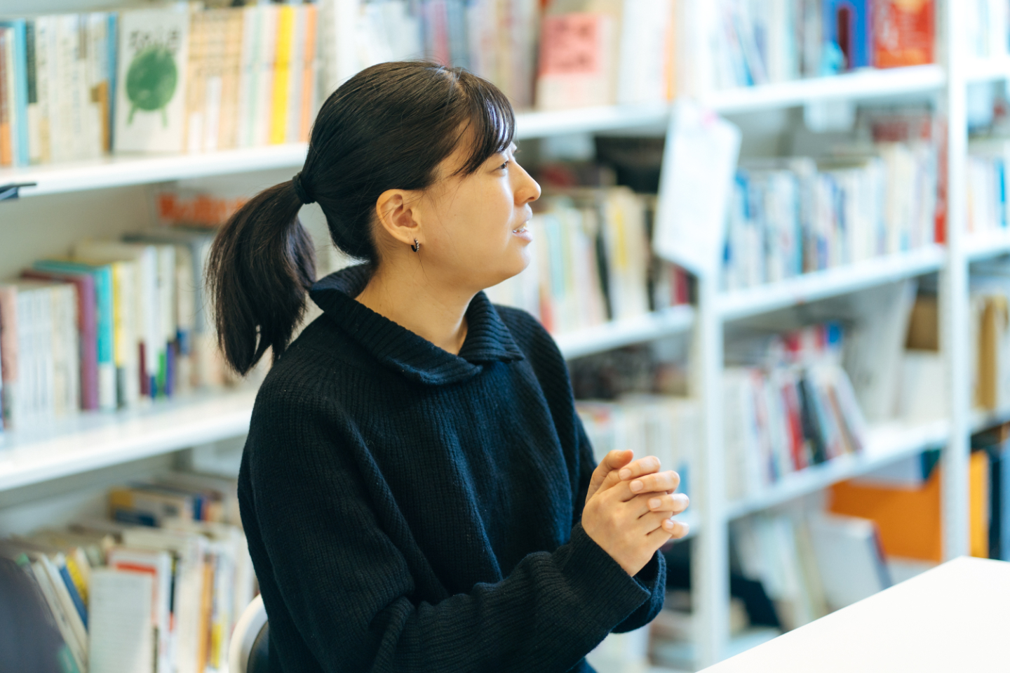 【写真】机に座り、平尾さんに向かって話す野口さんの横顔