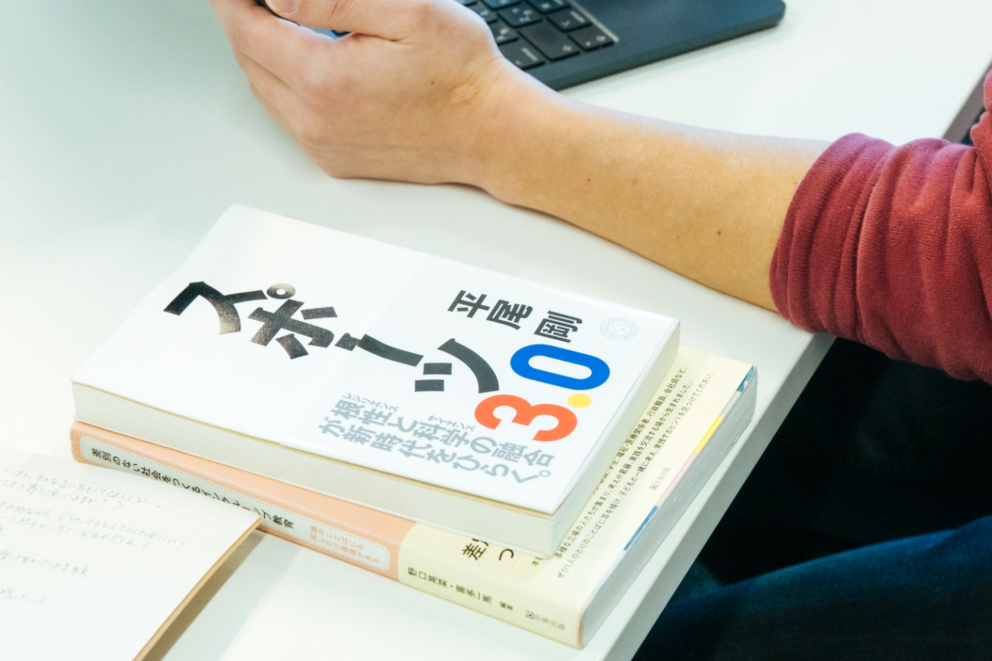 【写真】編集者の手元に、平尾さんの著書、スポーツ3.0が置かれている