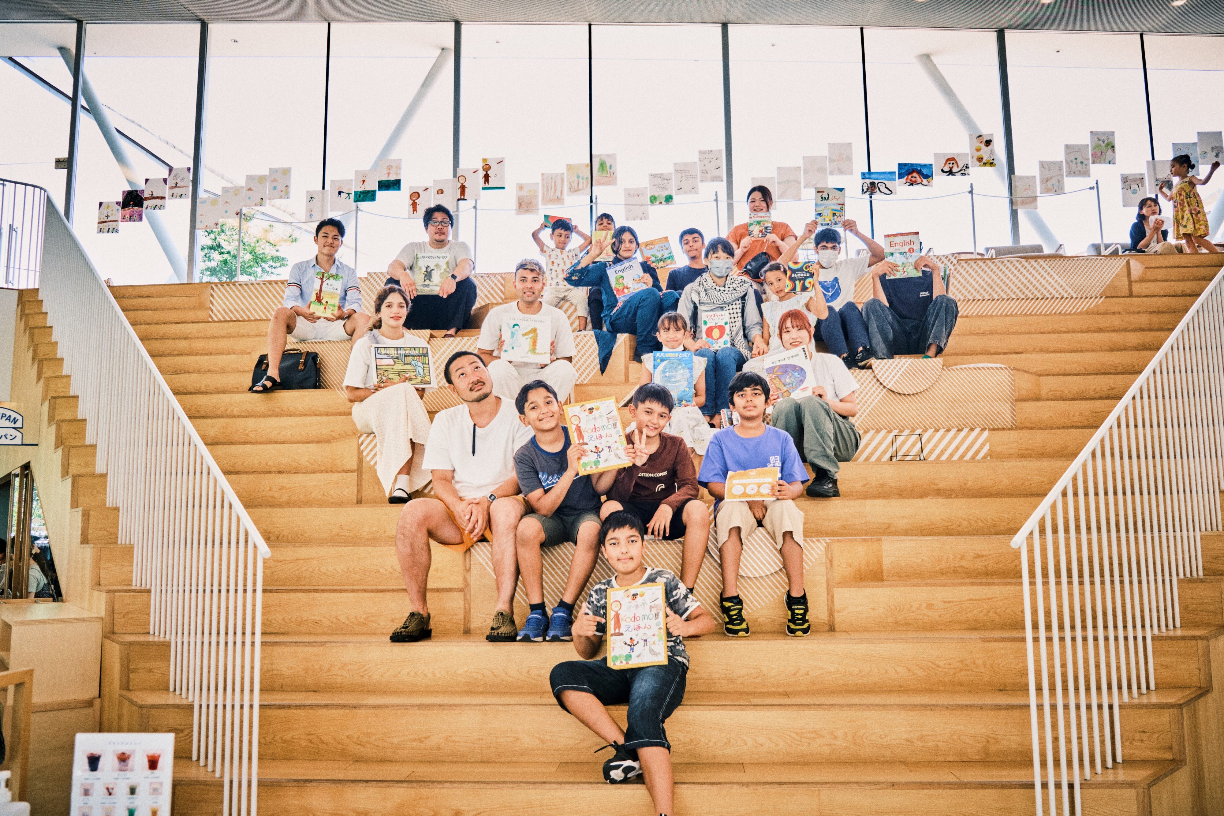 【写真】明るいホールの大階段に、たくさんの若者がこちらを向いて座っている