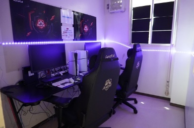 【写真】大きなモニターやゲームシステムがある机とリクライニングチェアのある部屋