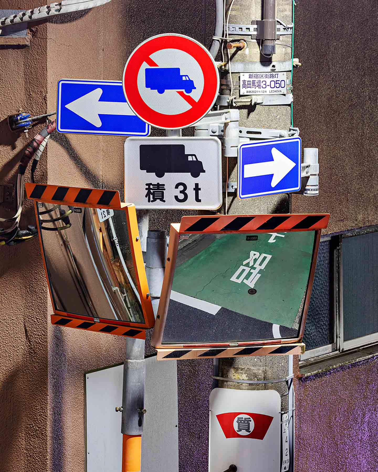 さまざまな標識やミラーが設置された複雑な指示を与える道路標識の写真作品。