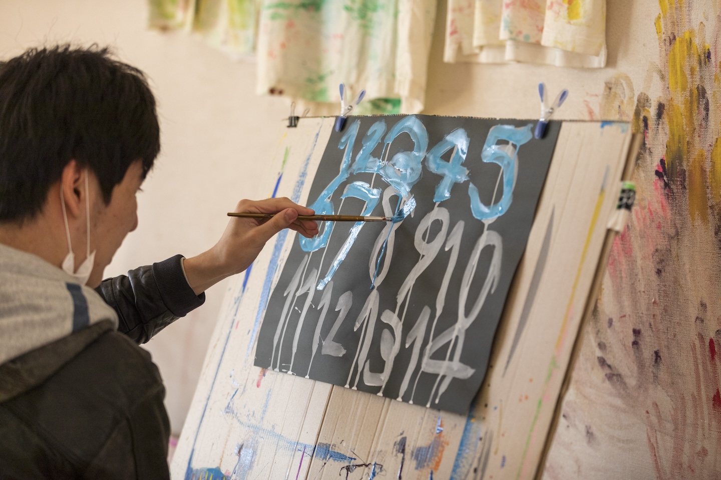 【写真】左手で絵筆を持ち、数字を描くメンバーの様子