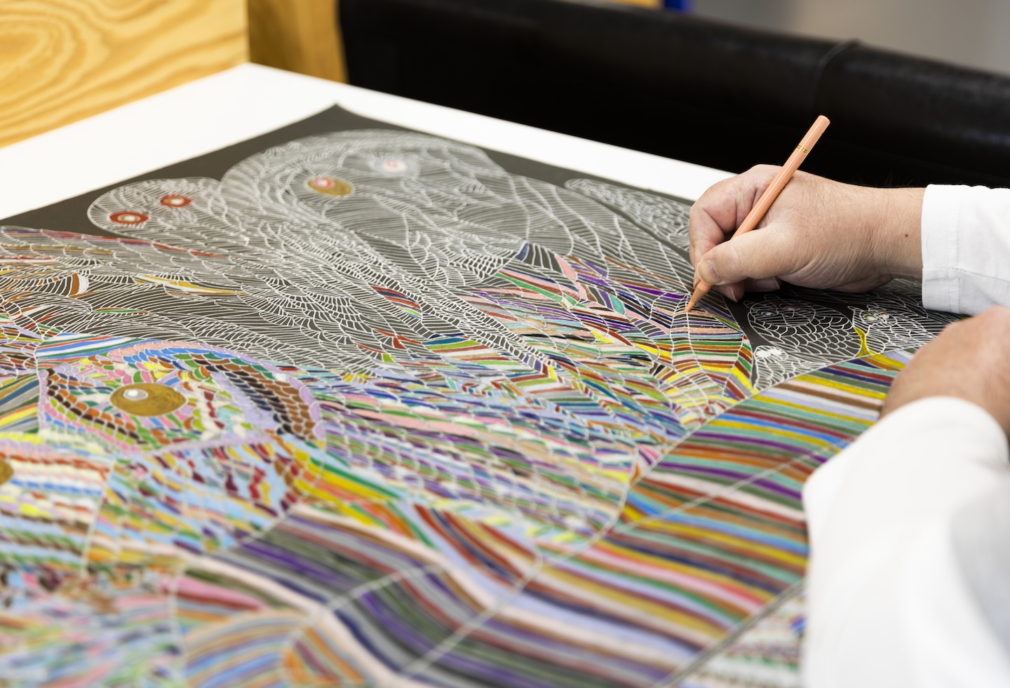 細密な絵を色鉛筆で色付けする手元