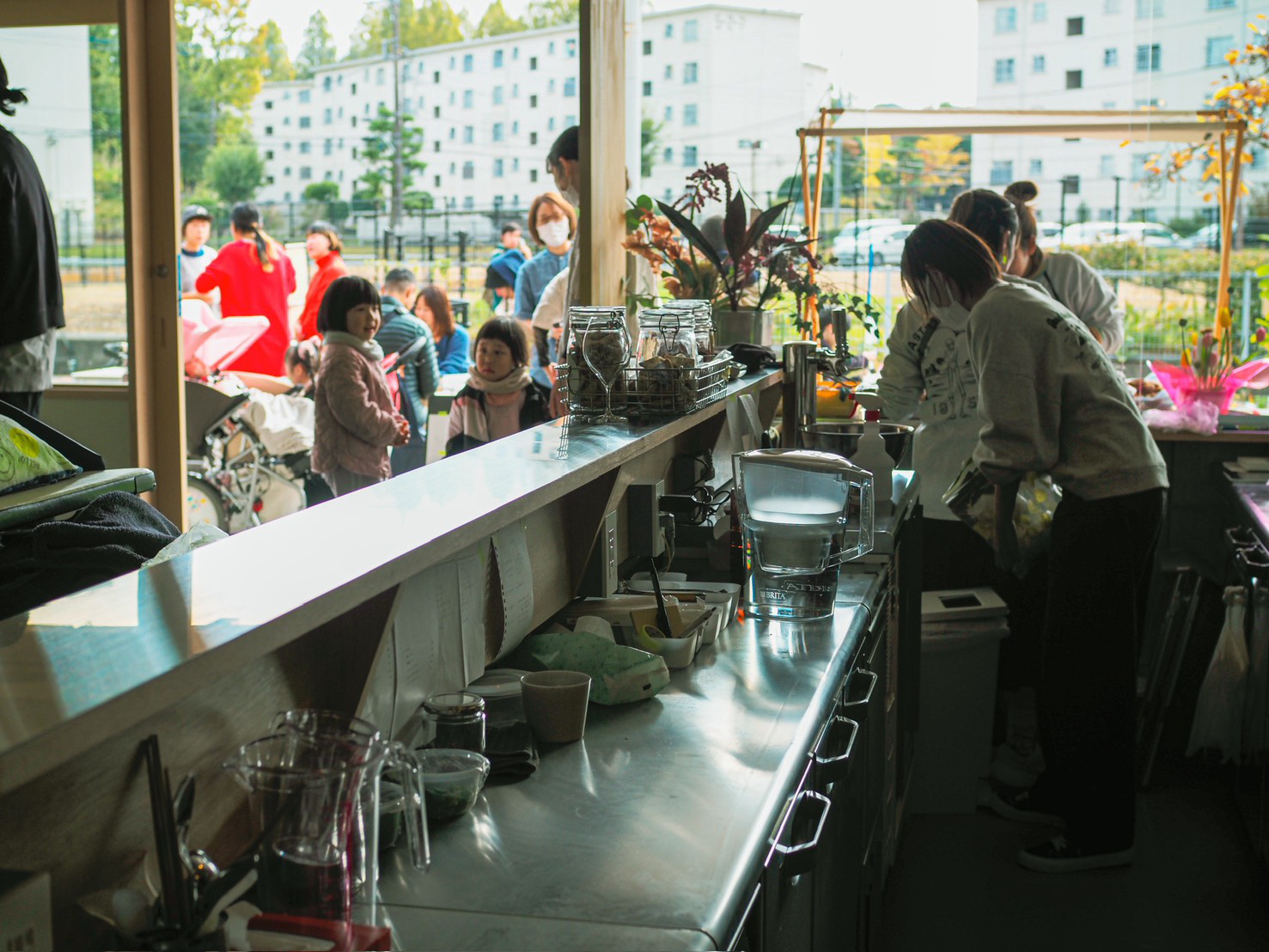 【写真】店内カウンターから外を見た写真。入り口に近くに子どもたちが屯ろし、向こうには公園や団地が見える
