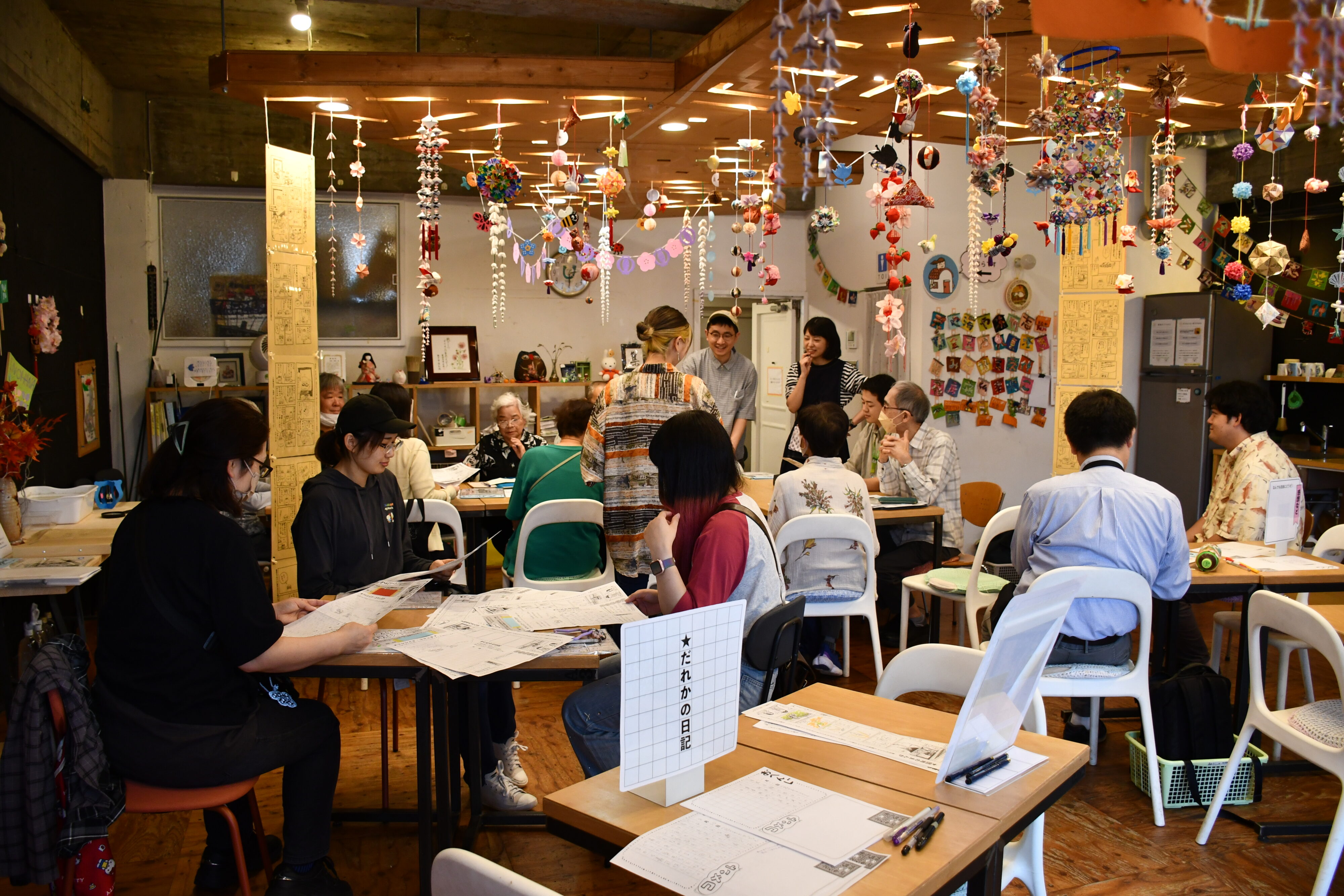 【写真】いくつものテーブルが並び、数人ずつが会話しているシーン