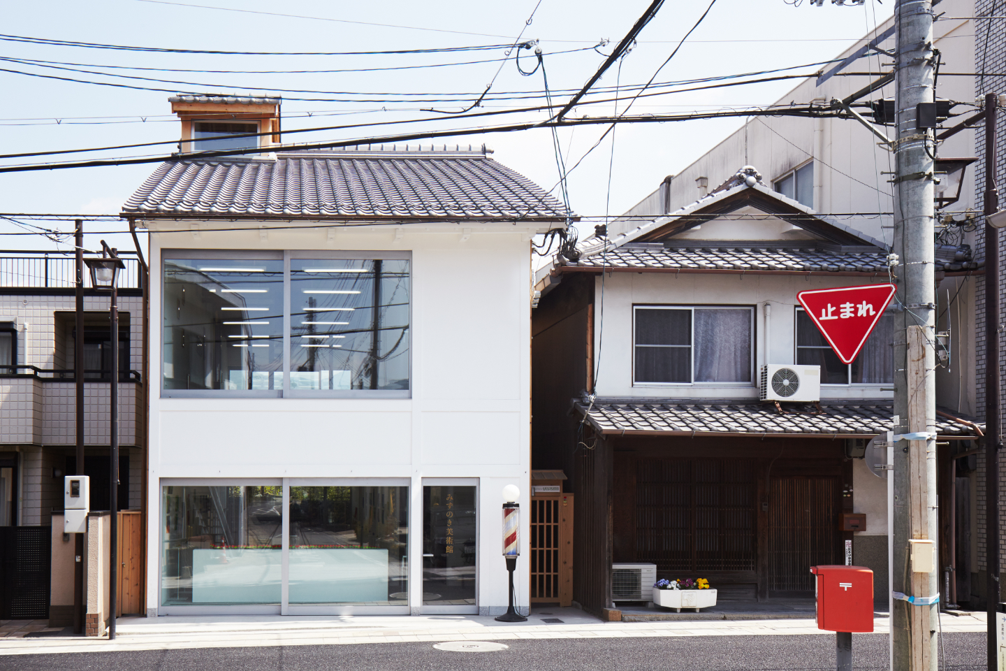 〈みずのき美術館〉の外観写真。建物右側の路上には、理髪店の名残であるサインポール（バーバーポール）が置かれてある