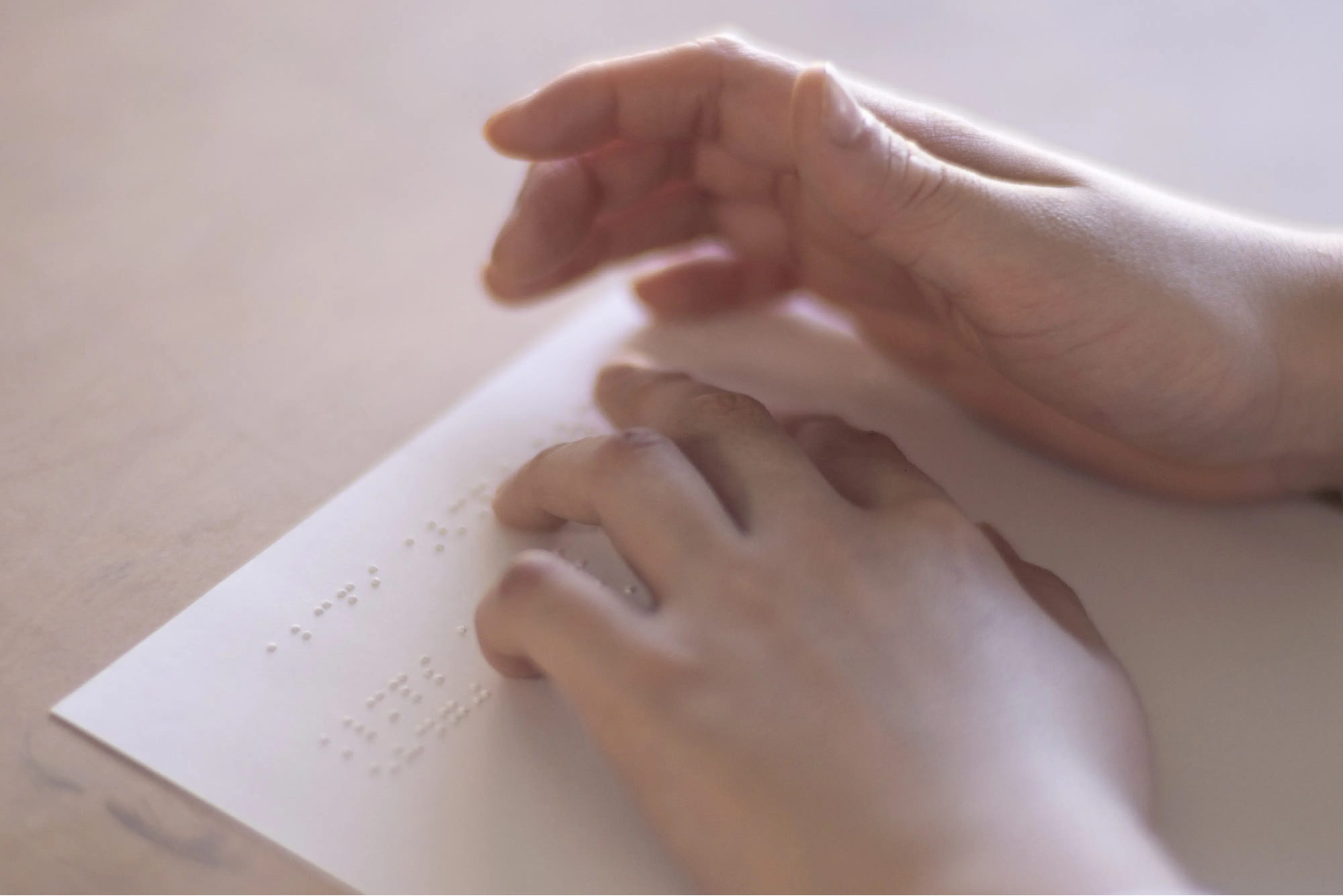 【写真】白い紙の上の展示を2本の手が読んでいる